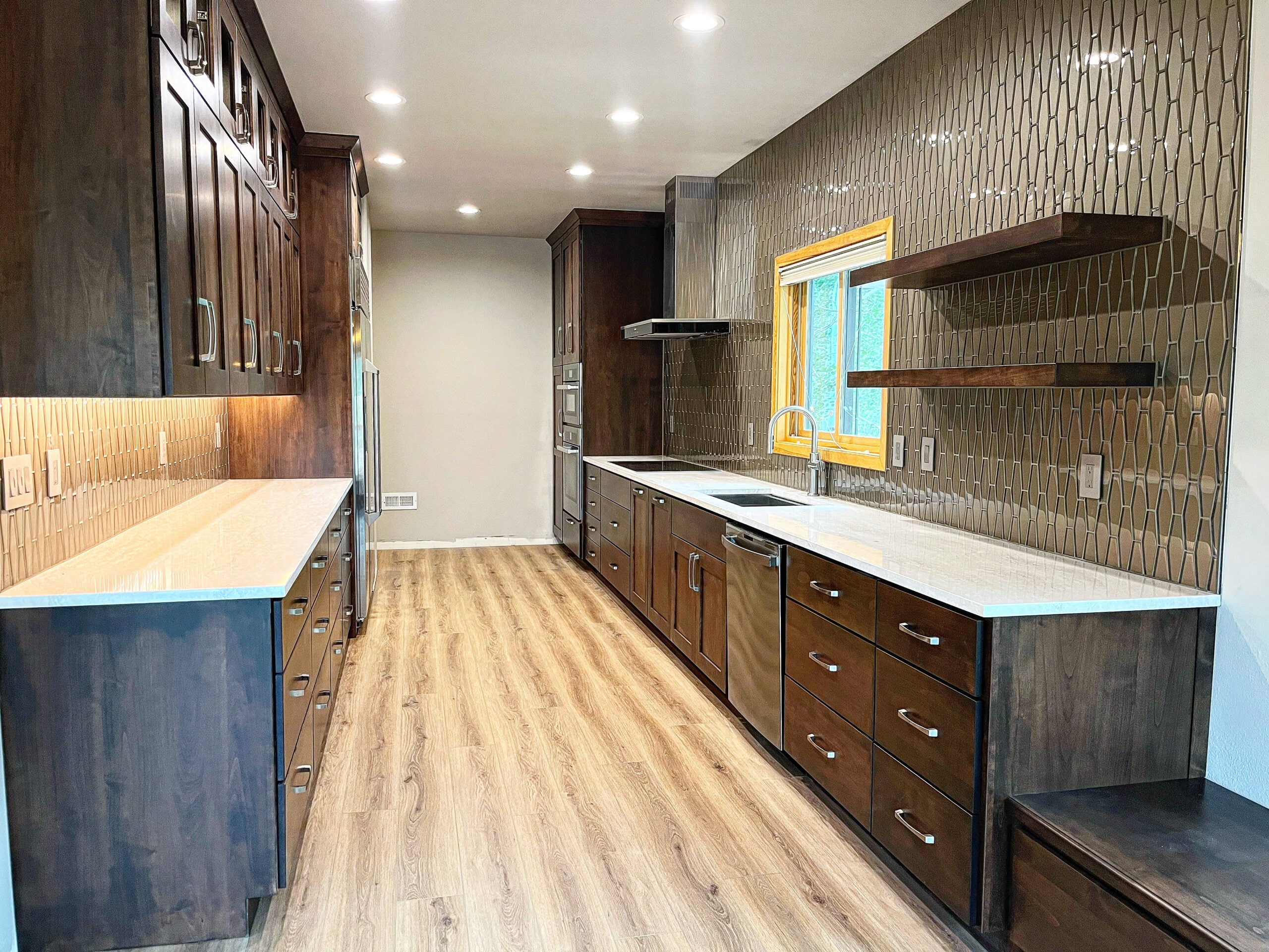 Modern Breckenridge kitchen remodel featuring dark wood cabinetry, white quartz countertops, geometric tile backsplash, and stainless steel appliances, showcasing a spacious and stylish design.