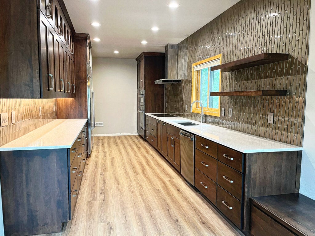 Modern kitchen interior featuring dark wood cabinetry, quartz countertops, and stylish backsplash, highlighting remodeling services in Frisco, CO.