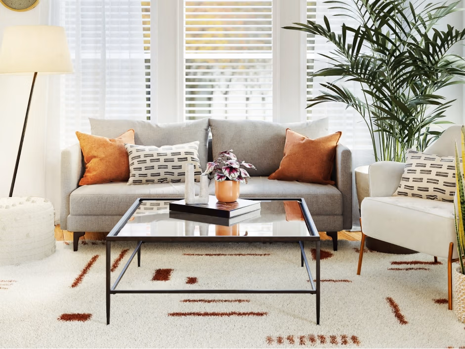 Modern living room with gray sofa, decorative pillows, glass coffee table, and potted plant, showcasing stylish interior design suitable for mountain homes.