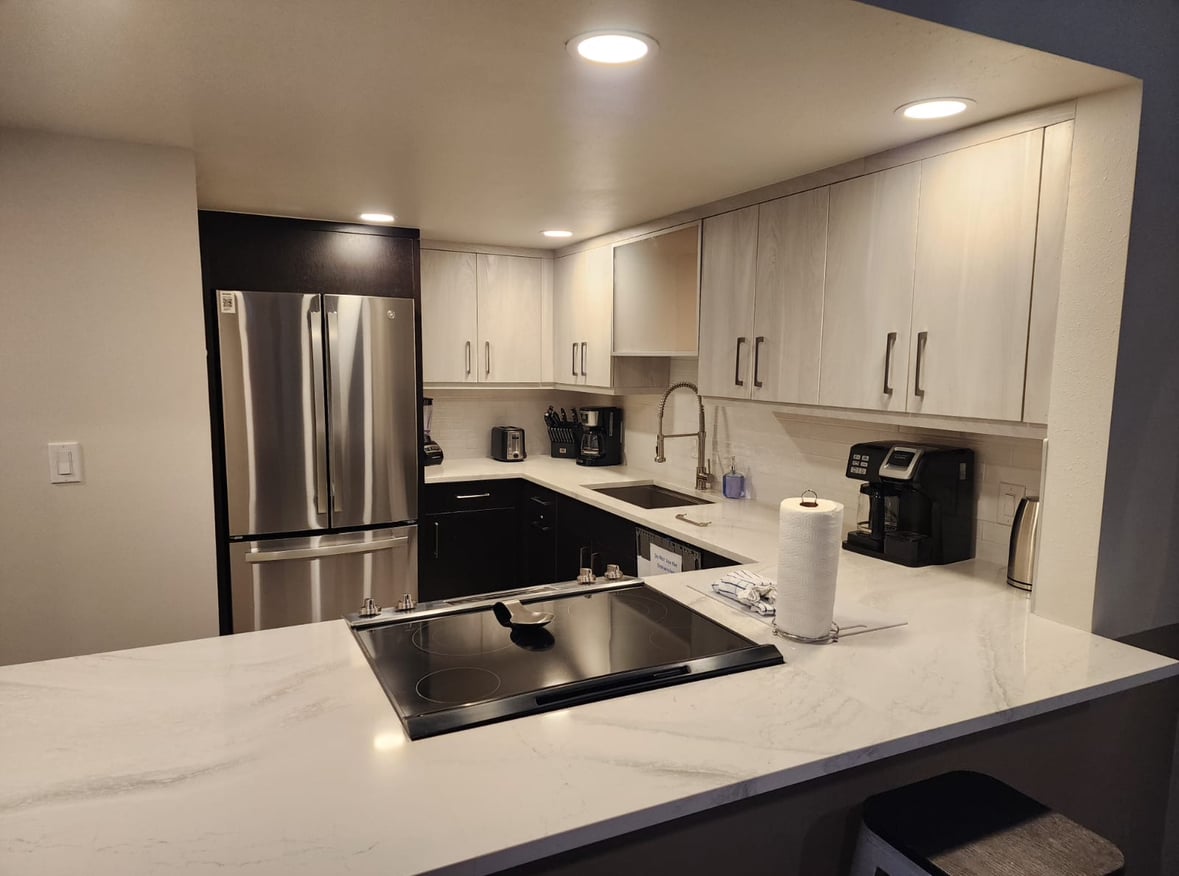 Modern kitchen remodel featuring stainless steel refrigerator, sleek cabinetry, quartz countertops, and contemporary appliances in Breckenridge.