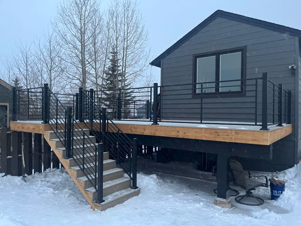 Deck and patio remodeling with modern railing and stairs, featuring a house in a snowy environment, highlighting outdoor renovation services in Frisco, Colorado.