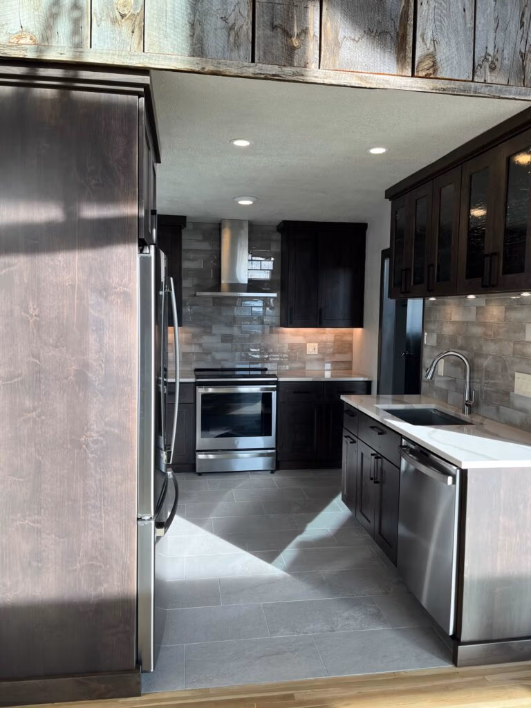 Modern kitchen remodel featuring dark cabinetry, stainless steel appliances, and natural stone countertops, designed for durability in mountain living.
