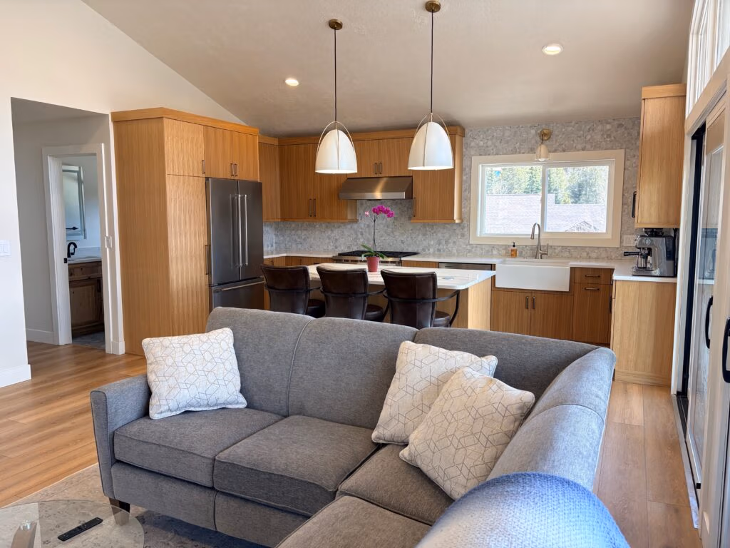 Modern kitchen and living area showcasing open layout, natural wood cabinetry, and stylish furnishings, designed for mountain living in Summit County, Colorado.
