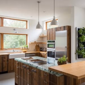 Modern kitchen featuring sustainable materials, energy-efficient appliances, wooden cabinetry, and natural light from large windows, emphasizing health and sustainability in home design.